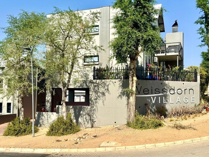 Exterior view of the Veissdorn Village apartment complex, featuring modern concrete architecture, secure boundary walls, and private balconies.