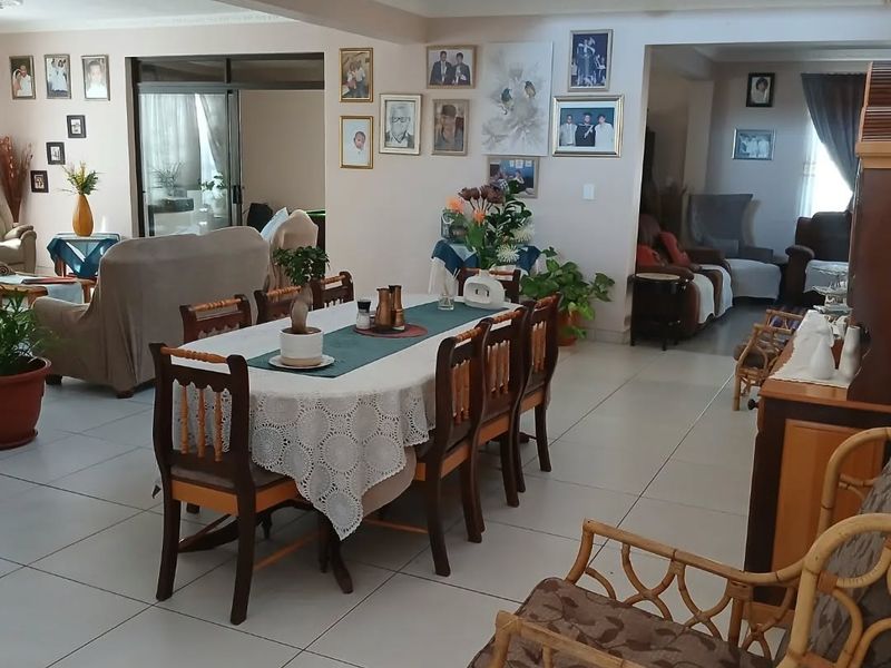 Spacious open-plan living and dining area featuring tiled flooring, a mezzanine level with a metal balustrade, and large sliding glass doors.
