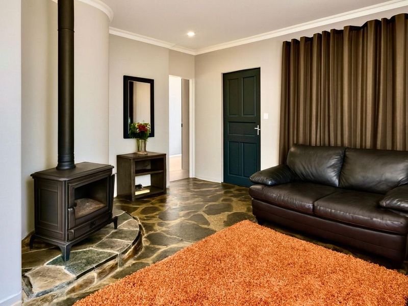 Cozy living room featuring unique flagstone flooring, a prominent freestanding wood-burning fireplace with a stone hearth, and elegant cove molding.