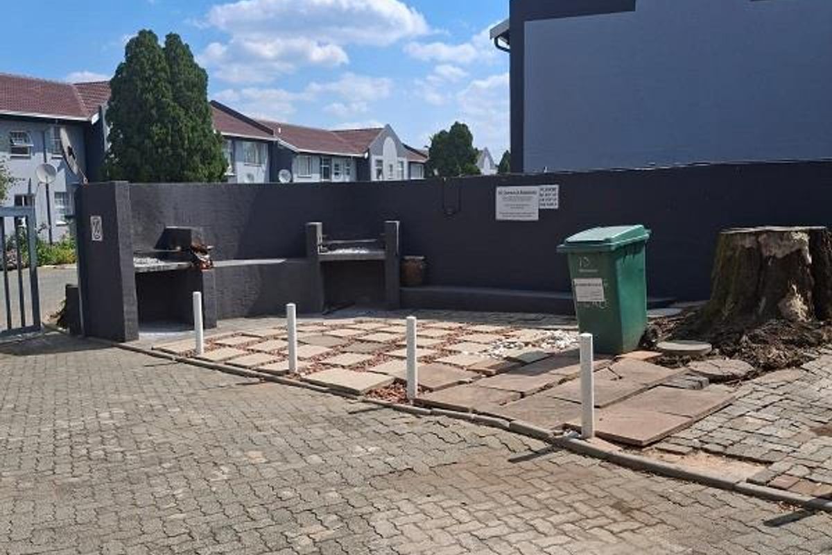 Outdoor communal area featuring built-in braai facilities, paved flooring, and perimeter walling within a townhouse complex.