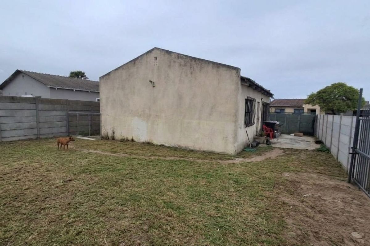 Rear view of the property featuring a large backyard enclosed by precast concrete boundary walls and a metal security gate.