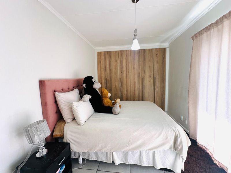 A well-maintained bedroom featuring built-in wooden cupboards, tiled flooring, and decorative cove cornicing, providing a clean and functional living space.