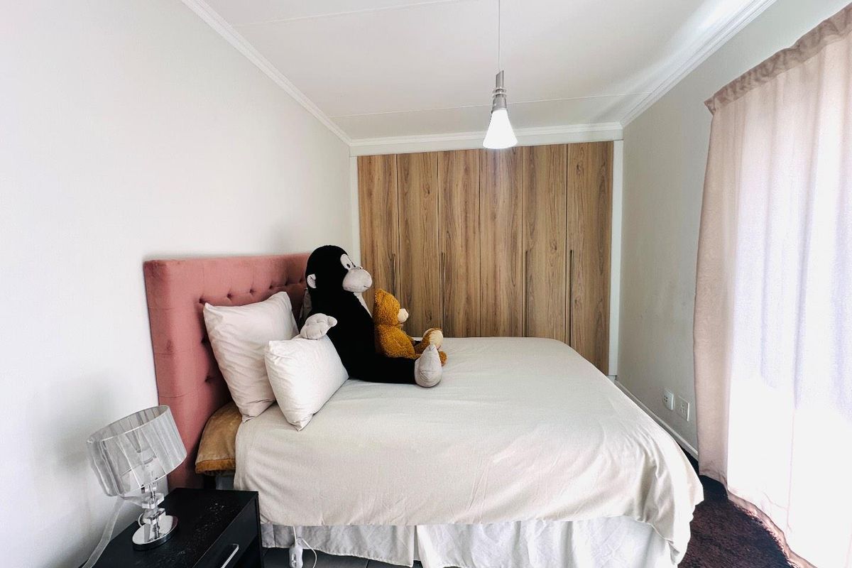 A well-maintained bedroom featuring built-in wooden cupboards, tiled flooring, and decorative cove cornicing, providing a clean and functional living space.