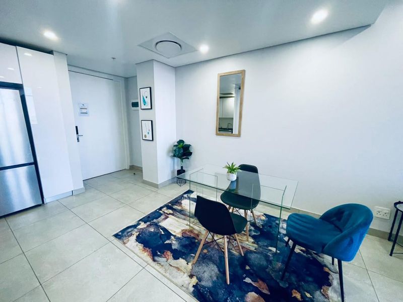 A modern, well-maintained living area featuring neutral tiled flooring, recessed ceiling lighting, and clean white walls.