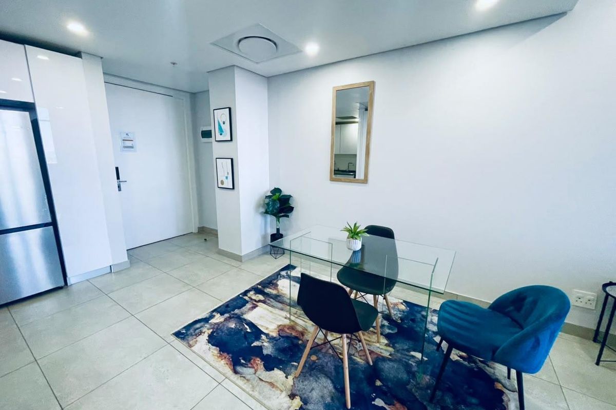 A modern, well-maintained living area featuring neutral tiled flooring, recessed ceiling lighting, and clean white walls.