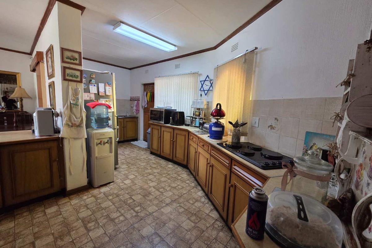 A functional kitchen featuring traditional wooden cabinetry, tiled backsplash, and built-in hob, offering a dated aesthetic ready for modern renovation.