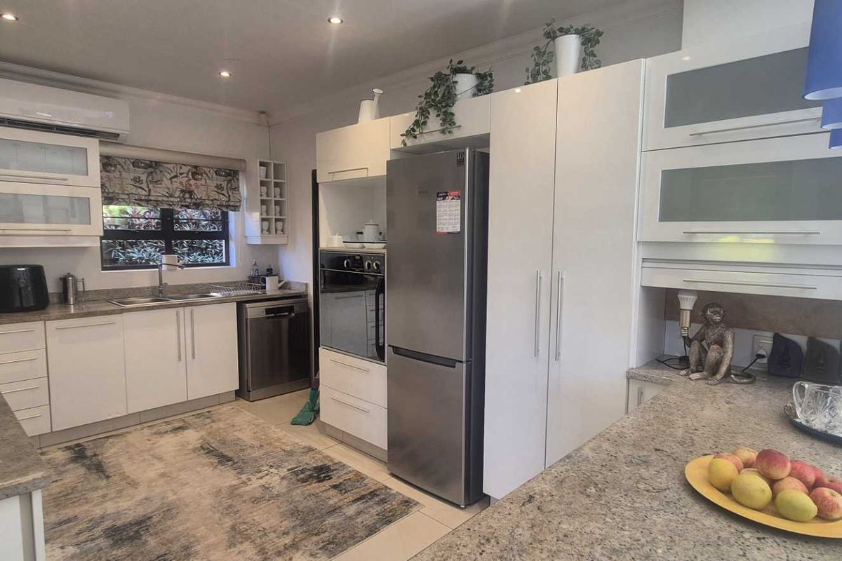 Modern kitchen featuring white cabinetry, granite countertops, built-in oven, extractor fan, and recessed lighting, offering a clean and functional workspace.