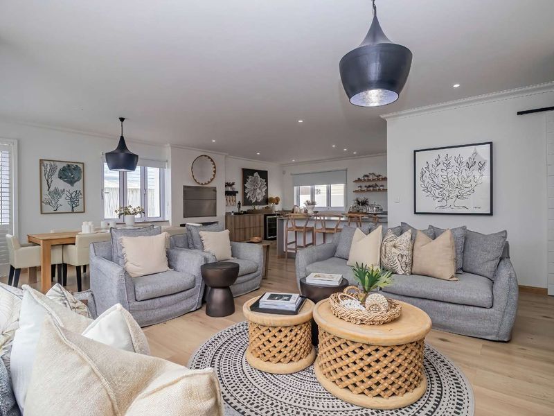 Spacious open-plan living and dining area featuring light timber flooring, modern kitchen island, and elegant recessed lighting throughout.