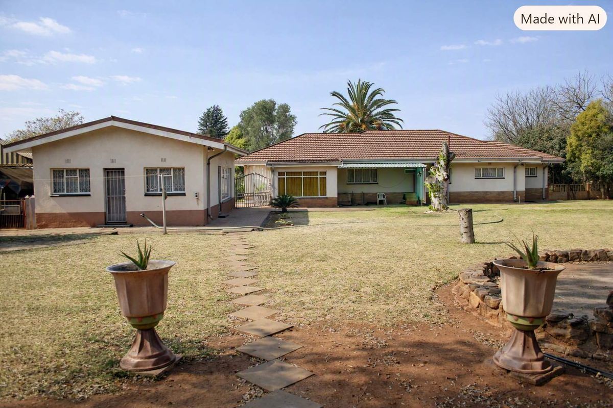 Rear view of the property featuring a spacious garden, paved walkway, and two separate building structures with tiled roofs.