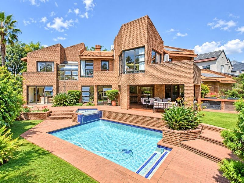 Spacious rear exterior featuring a brick-faced multi-level home, a swimming pool with integrated water feature, and a paved patio area perfect for outdoor entertaining.