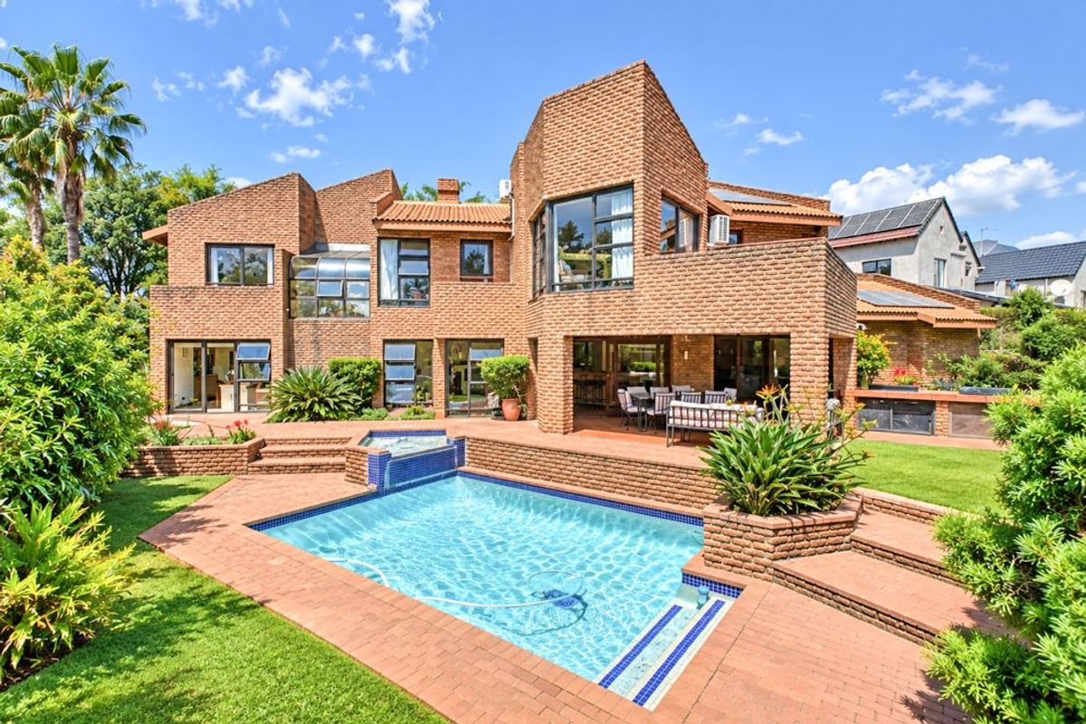 Spacious rear exterior featuring a brick-faced multi-level home, a swimming pool with integrated water feature, and a paved patio area perfect for outdoor entertaining.