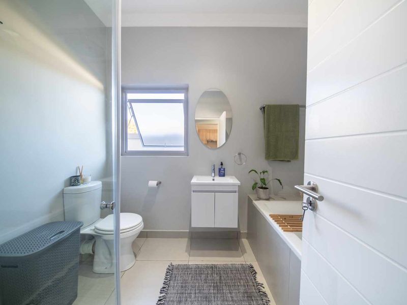A modern, well-maintained bathroom featuring a shower enclosure, a bathtub, a vanity with basin, and neutral tiled flooring.