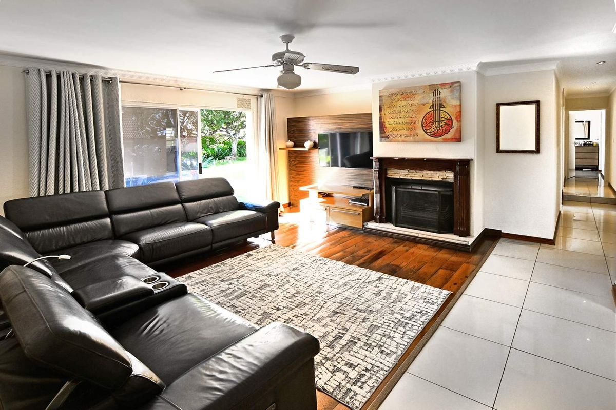Spacious living room featuring hardwood flooring, a built-in fireplace with a wooden mantel, and sliding glass doors providing access to the garden.