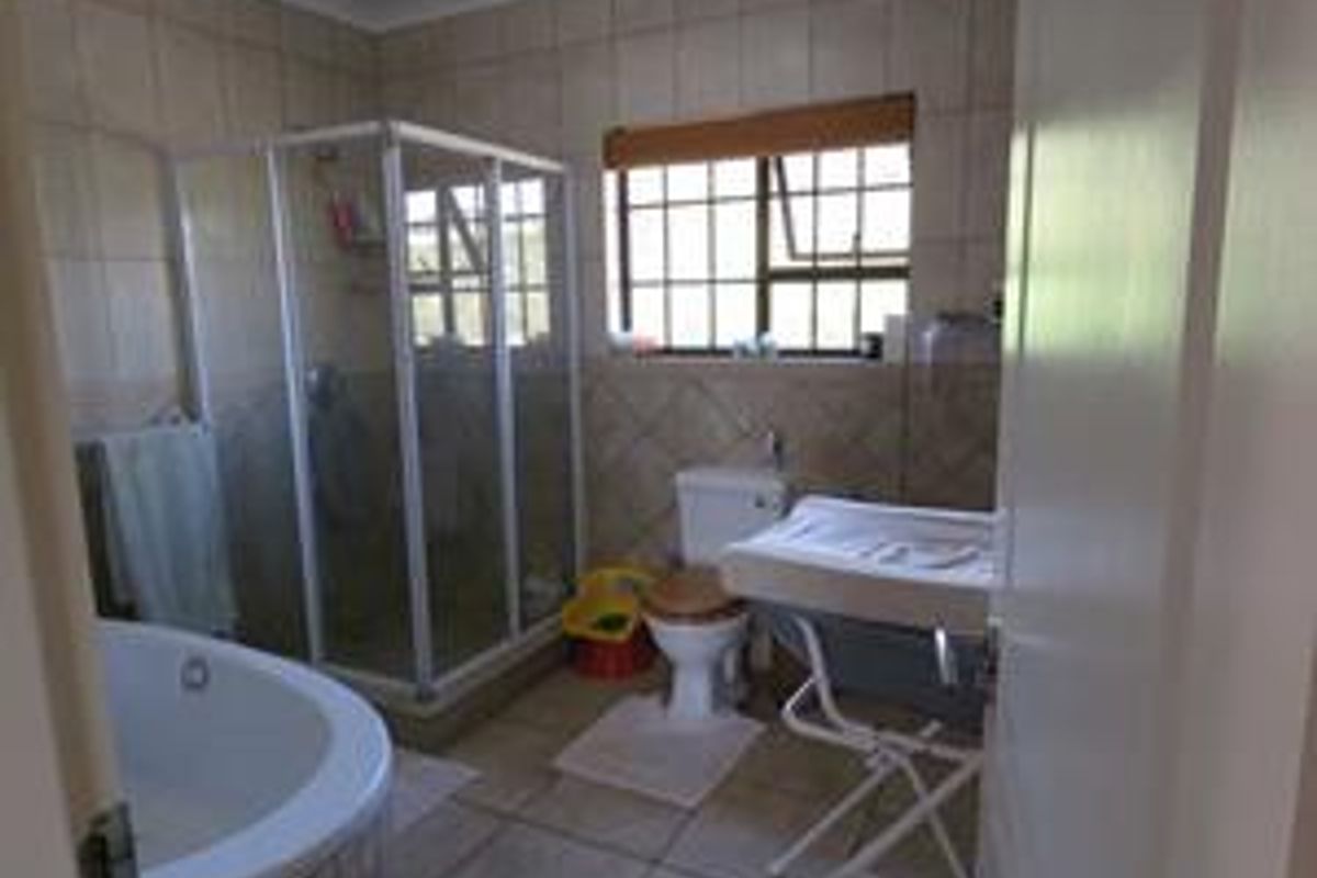 A functional bathroom featuring a corner bathtub, a separate glass-enclosed shower, a toilet, and tiled walls and flooring.