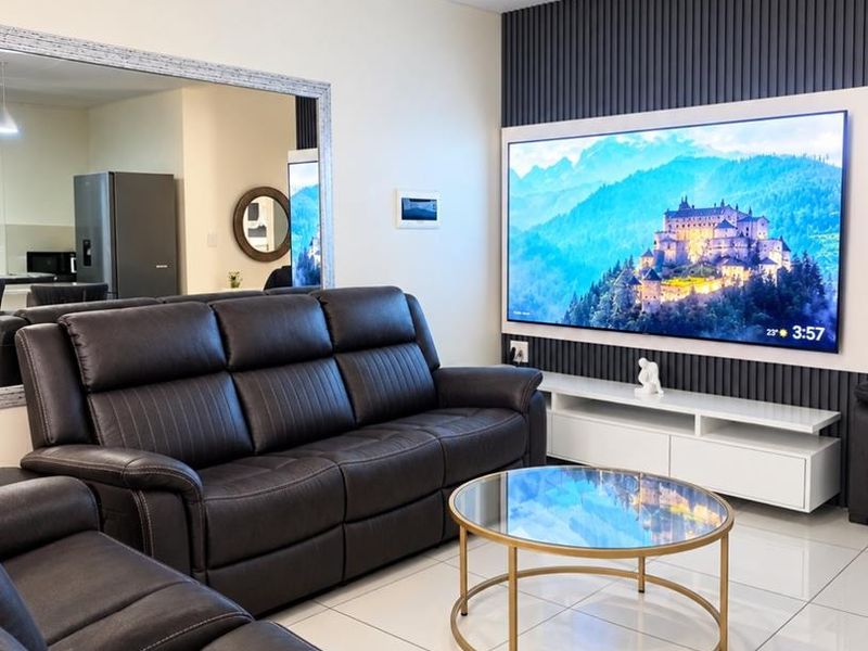 A modern living room featuring a decorative slatted feature wall, large wall mirror, and polished tiled flooring.