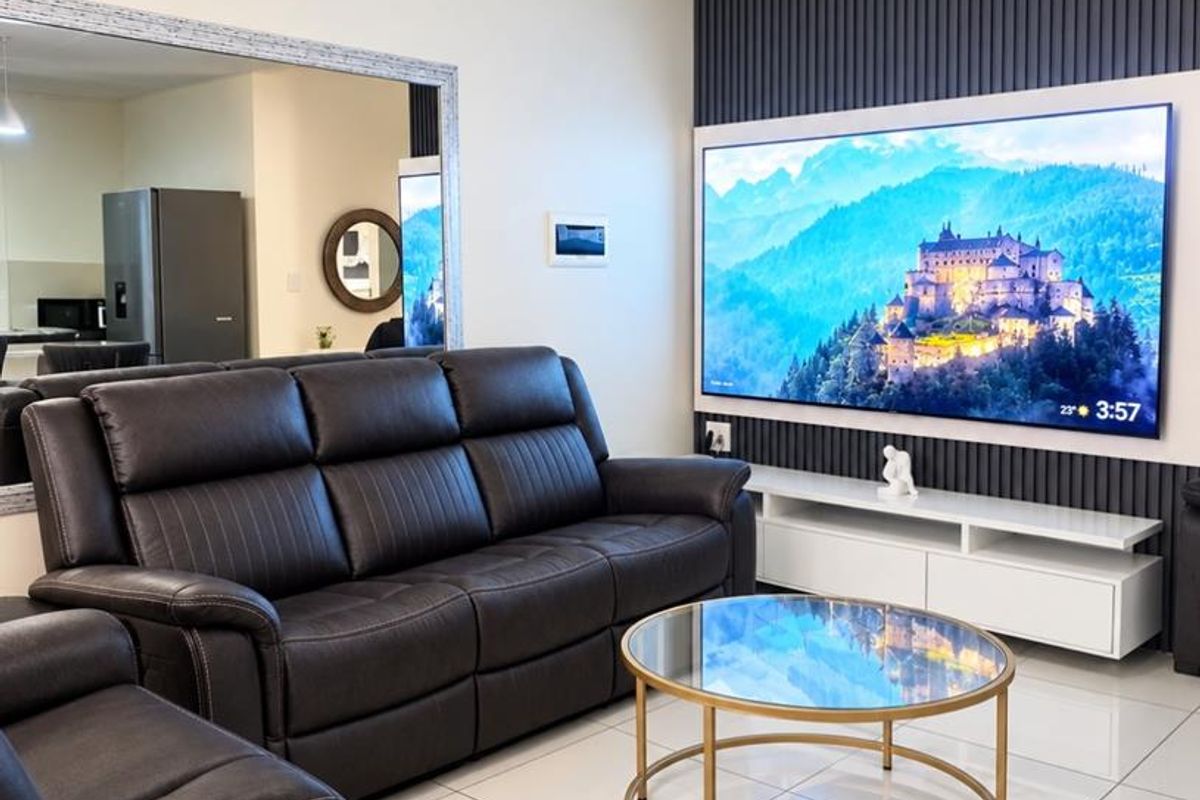 A modern living room featuring a decorative slatted feature wall, large wall mirror, and polished tiled flooring.