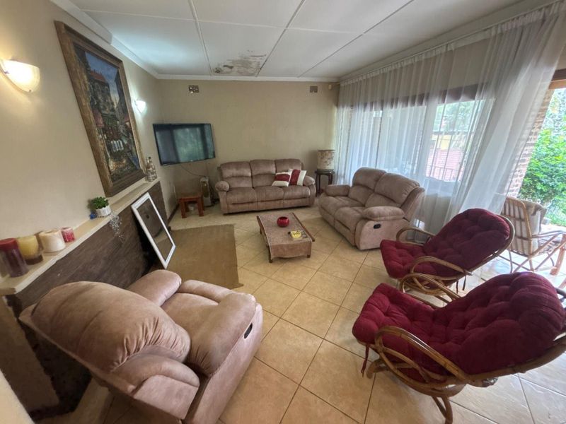 A living room featuring tiled flooring and large windows, currently showing visible water damage on the ceiling tiles.