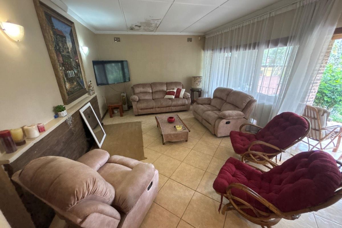 A living room featuring tiled flooring and large windows, currently showing visible water damage on the ceiling tiles.