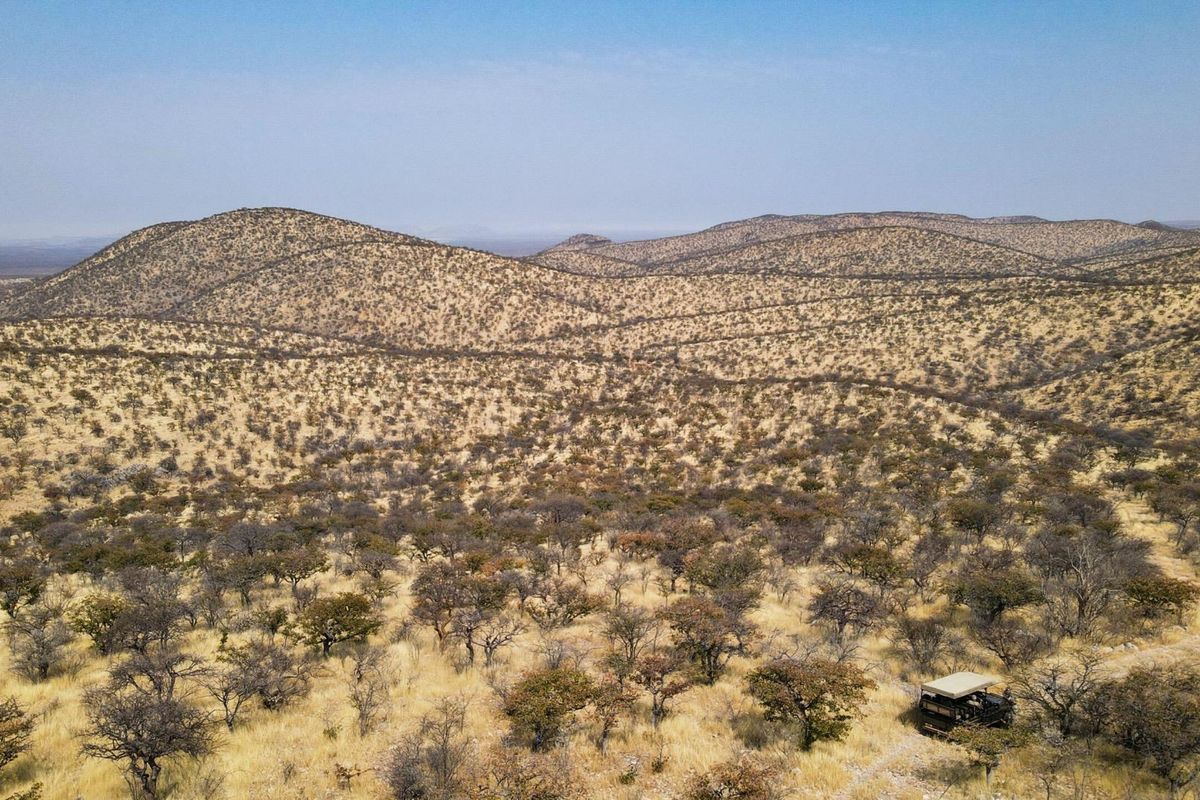An expansive aerial view of the rugged, arid landscape surrounding the lodge, showcasing the natural terrain and vast open space.