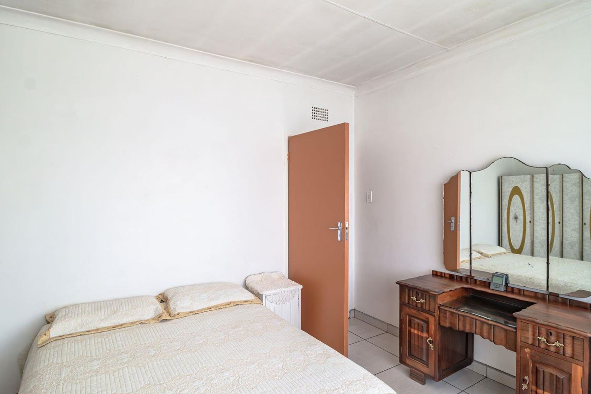 A simple bedroom featuring tiled flooring and a standard interior door, providing a functional and neutral living space.