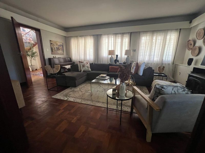 Spacious living room featuring classic parquet flooring and a built-in fireplace, offering a warm and inviting atmosphere with ample natural light.