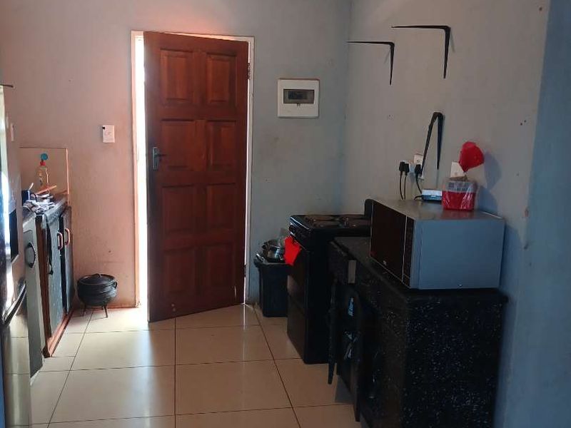 A functional kitchen area featuring tiled flooring, built-in cabinetry, and a stove, requiring cosmetic updates to improve the overall aesthetic.