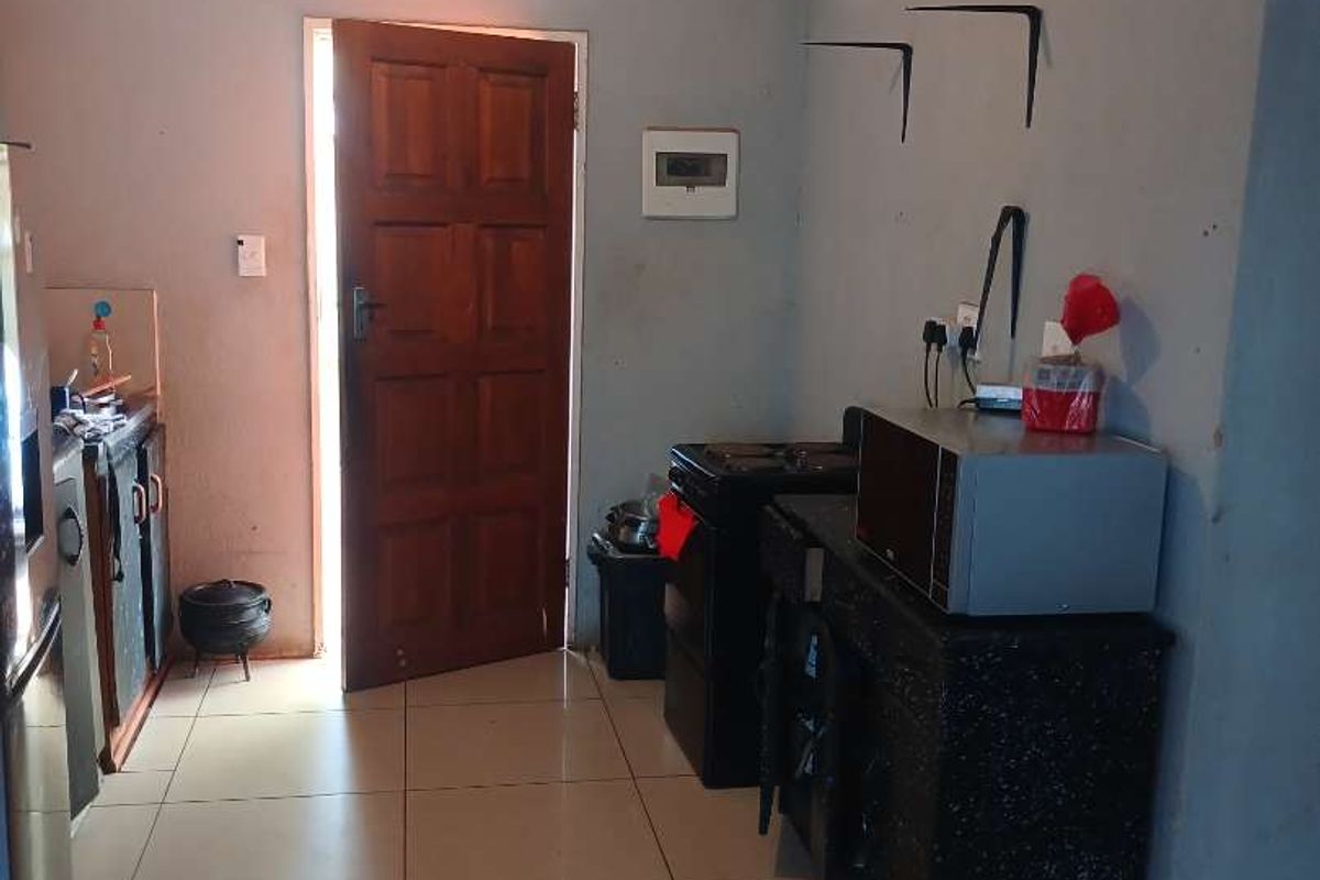 A functional kitchen area featuring tiled flooring, built-in cabinetry, and a stove, requiring cosmetic updates to improve the overall aesthetic.