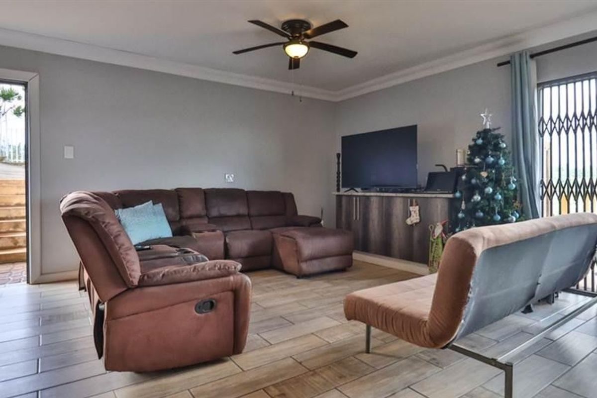 A comfortable living room featuring tiled flooring, a ceiling fan, and built-in cabinetry, with direct access to an outdoor area through a security gate.