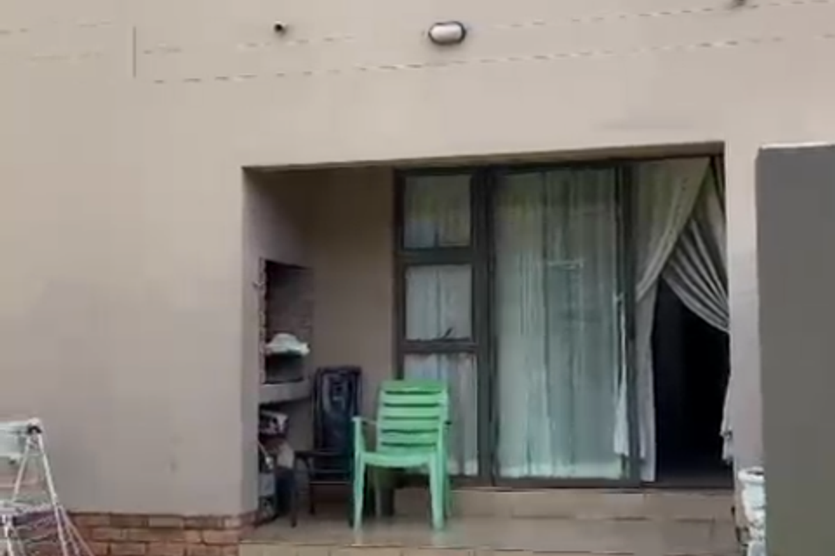Rear view of the apartment featuring a paved patio area, built-in braai, and access to the living space via sliding glass doors.