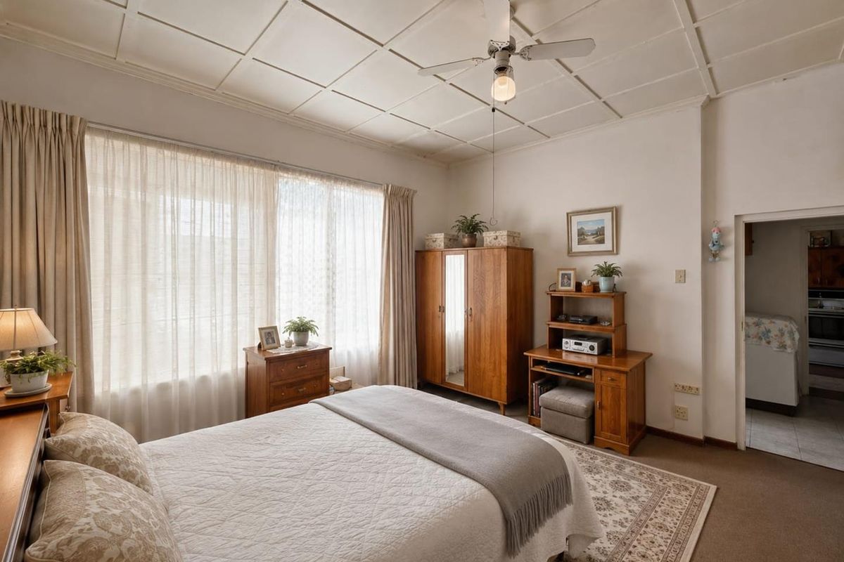 A well-maintained bedroom featuring a ceiling fan, tiled ceiling, and carpeted flooring, with natural light filtering through large windows.