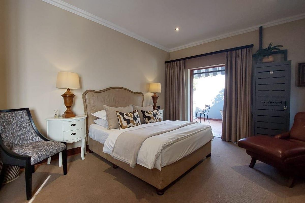 A well-maintained bedroom featuring neutral carpeting, crown molding, and direct access to an outdoor patio through sliding glass doors.