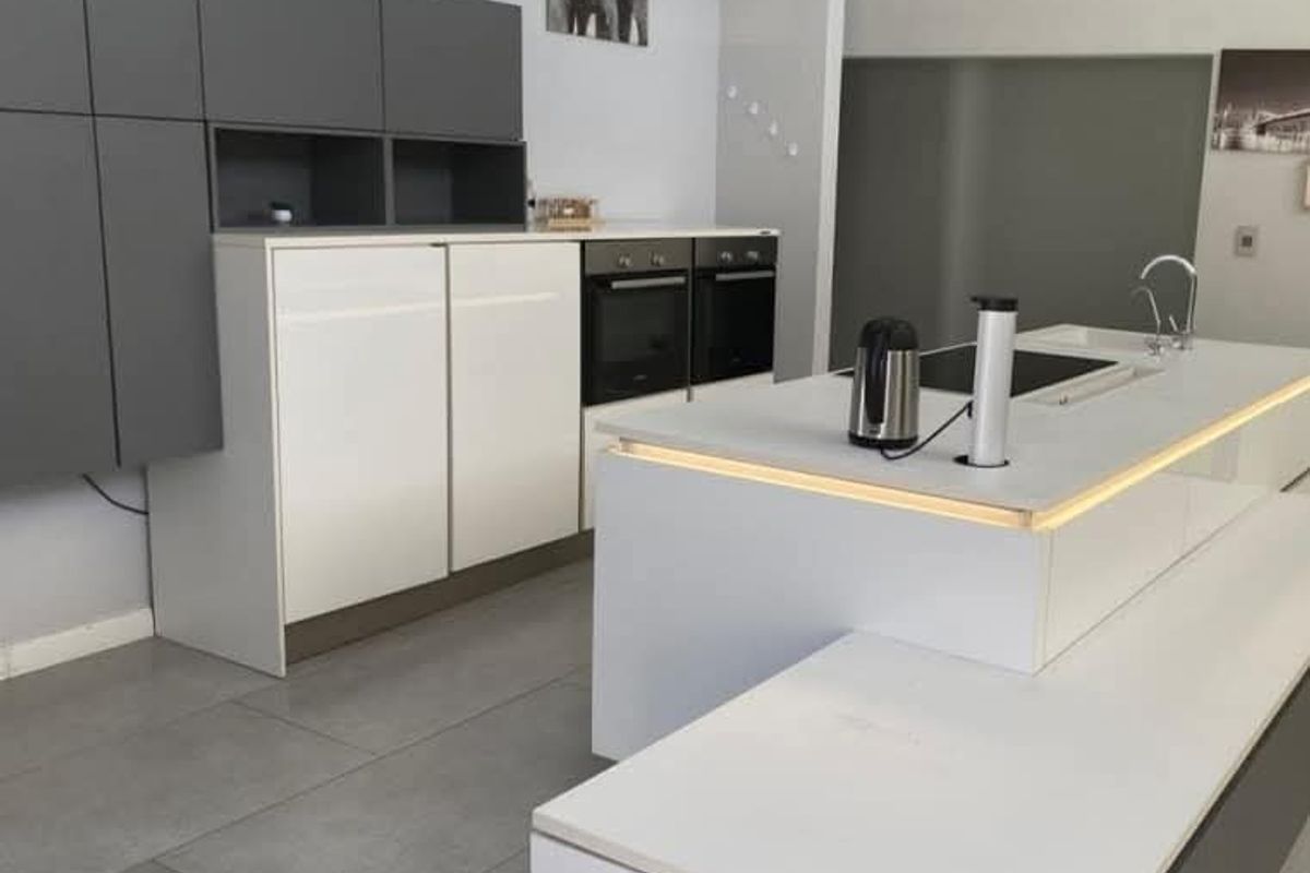 Modern kitchen featuring a central island with integrated hob, dual built-in ovens, sleek cabinetry, and large format floor tiles.