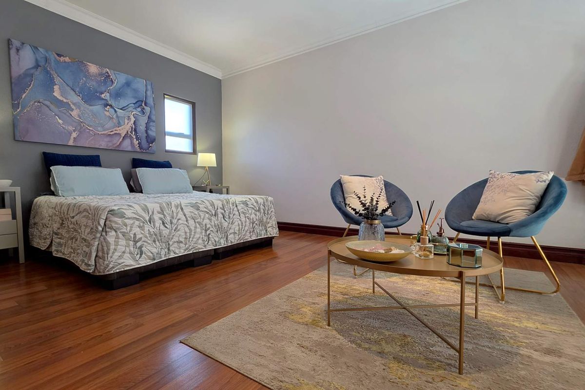 Spacious bedroom featuring warm hardwood flooring, neutral wall tones, and classic cove cornicing, providing a comfortable and well-maintained living space.