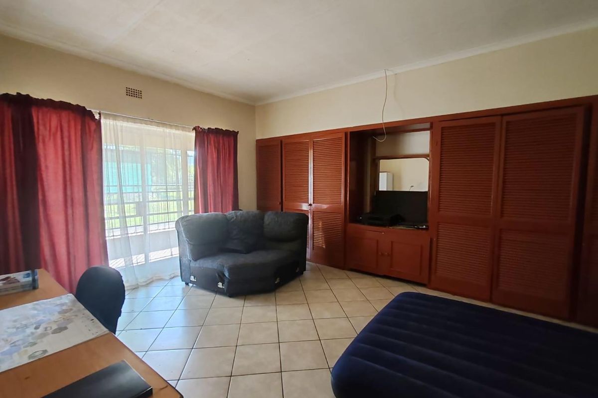 Spacious bedroom featuring extensive built-in wooden cabinetry, tiled flooring, and a sliding glass door providing access to the exterior.