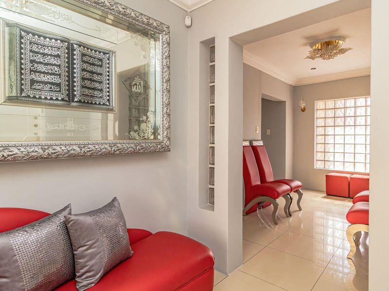A bright living area featuring polished tile flooring, decorative glass block wall accents, and elegant cove molding, creating a modern and well-maintained interior space.