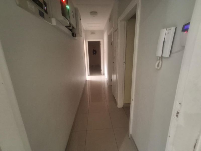 A functional hallway featuring tiled flooring, an intercom system, and wall-mounted electrical infrastructure including an inverter unit.