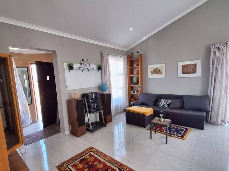 A bright living room featuring vaulted ceilings, recessed downlighting, and polished tiled flooring, creating an open and airy atmosphere.
