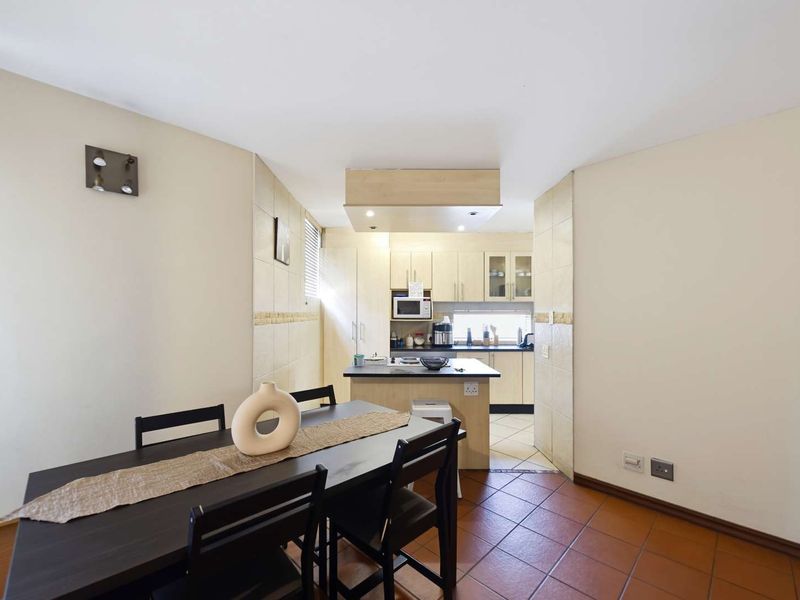 Open plan kitchen and dining area featuring tiled flooring, built-in cabinetry, and a central kitchen island.