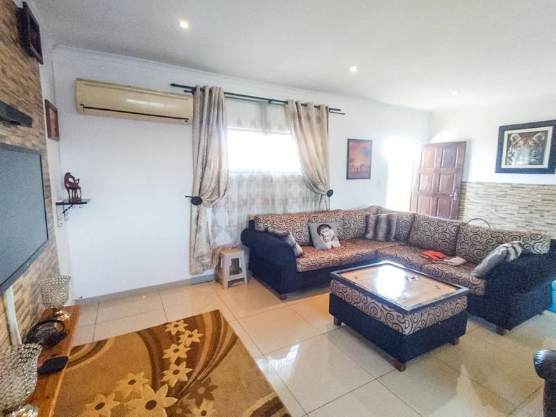 A living room featuring tiled flooring, a stone-cladding feature wall, and a wall-mounted split-system air conditioner.