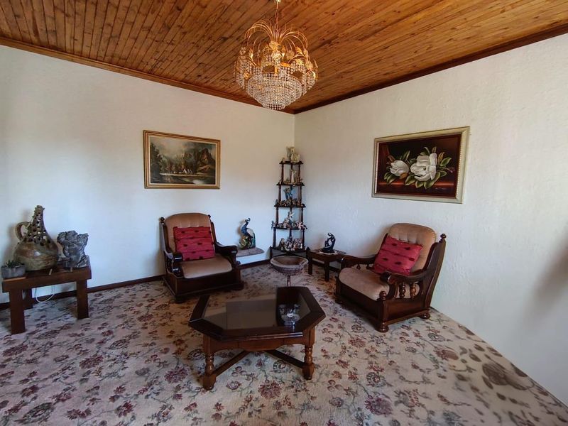A traditional living room featuring a timber tongue and groove ceiling, a crystal chandelier, and patterned carpet flooring.