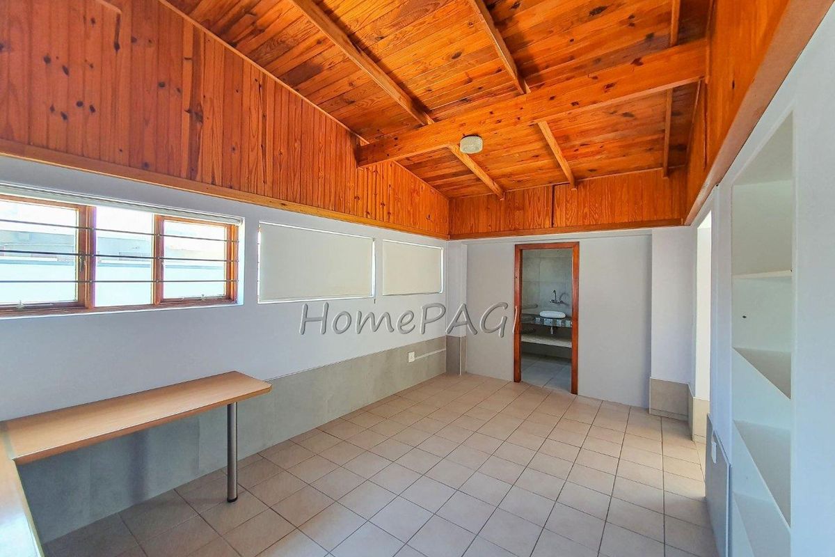A functional room featuring a vaulted timber-paneled ceiling, tiled flooring, and an adjoining bathroom, offering a versatile space for various uses.