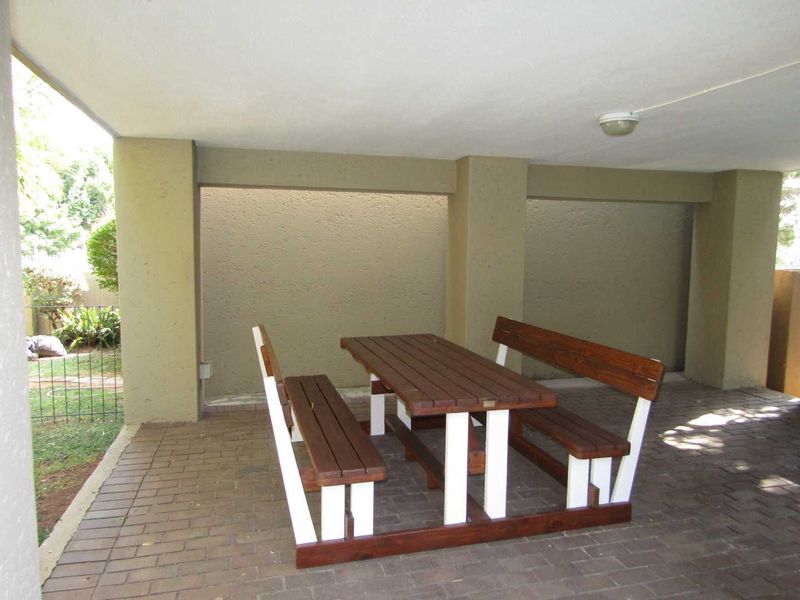 A covered patio area featuring brick paving and structural concrete pillars, providing a functional outdoor space for relaxation.
