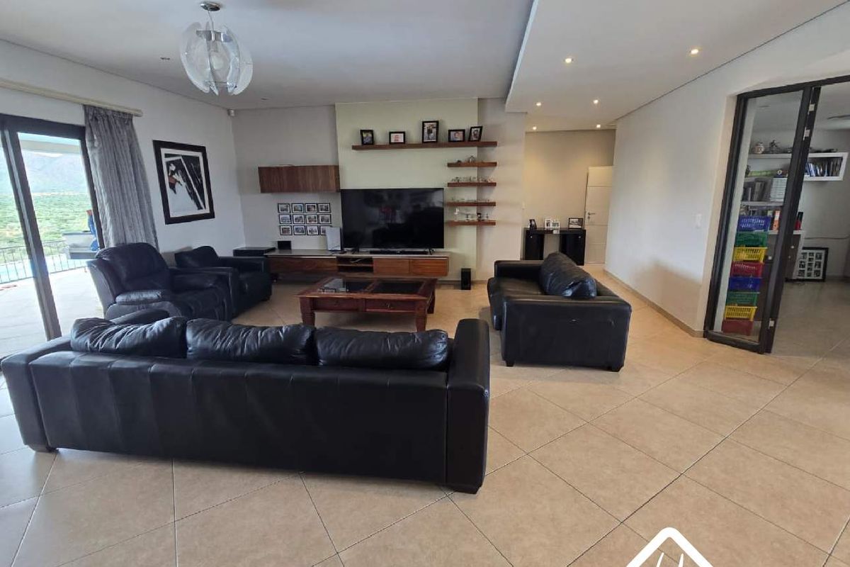 Spacious living room featuring tiled flooring, recessed ceiling lighting, and a glass-paneled door leading to an adjacent room.