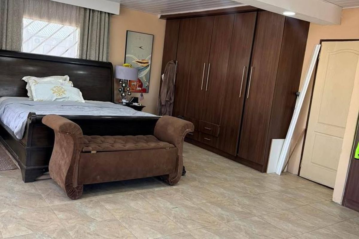 Spacious bedroom featuring large built-in wooden wardrobes, tiled flooring, and recessed ceiling lighting.
