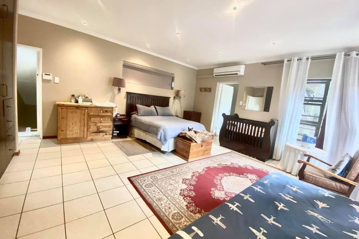 Spacious bedroom featuring tiled flooring, recessed ceiling lighting, and a wall-mounted air conditioning unit.