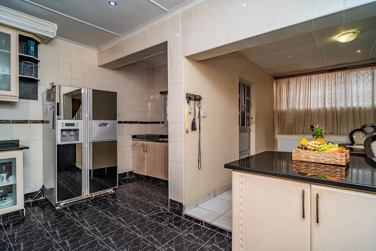 A functional kitchen featuring dark granite countertops, tiled flooring, and wall-mounted cabinetry, offering a practical layout with potential for modern cosmetic updates.