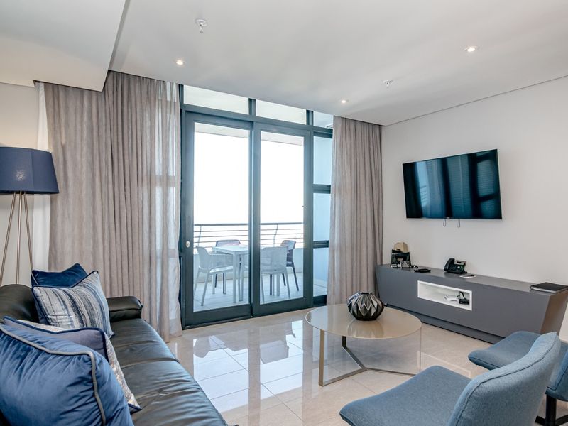 Modern living room featuring polished tile flooring, recessed lighting, and large sliding glass doors providing access to a private balcony.