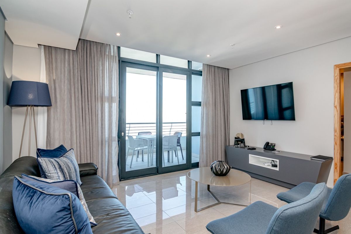 Modern living room featuring polished tile flooring, recessed lighting, and large sliding glass doors providing access to a private balcony.
