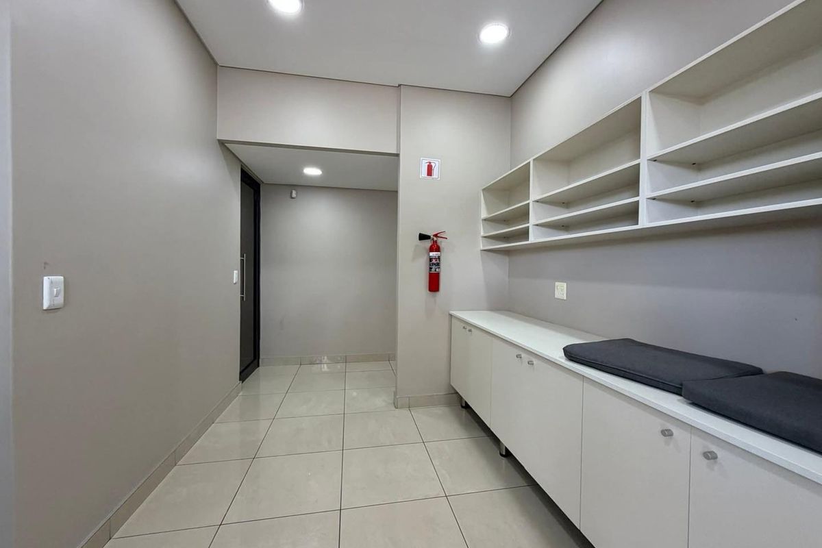 A clean and functional utility space featuring ample built-in cabinetry, open shelving, and modern tiled flooring, suitable for storage or administrative use.