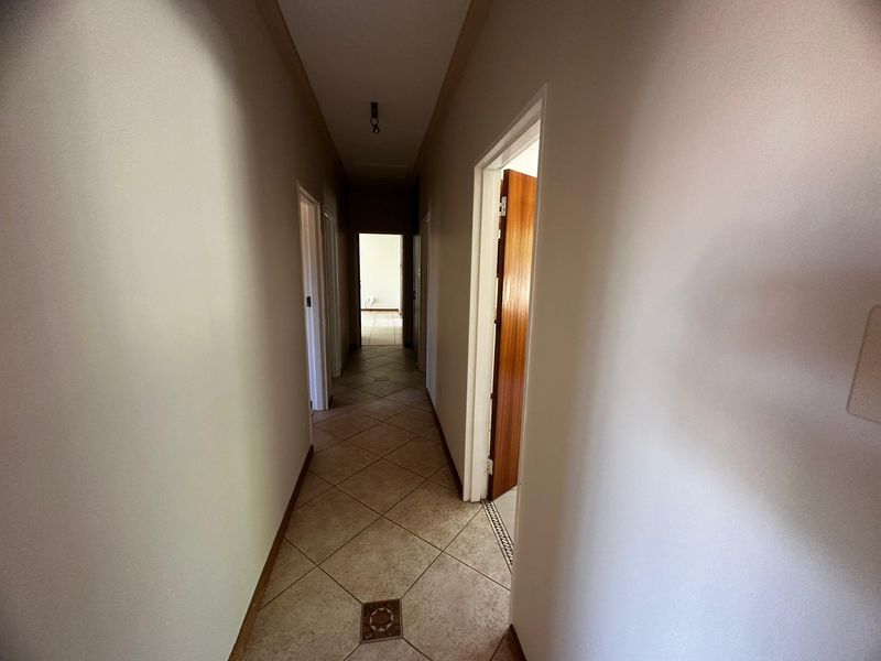 A functional hallway featuring neutral tiled flooring and access to multiple rooms, providing a clean and simple transition space within the home.